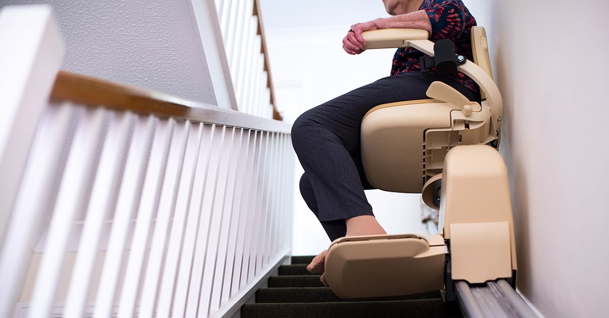 Elderly woman riding a stair lift in her home