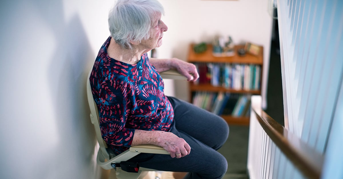 Eldery woman riding a stair lift in her home