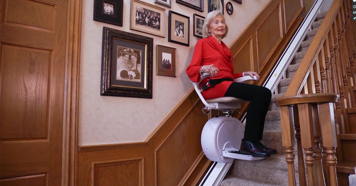 Senior woman riding a stair lift in her home